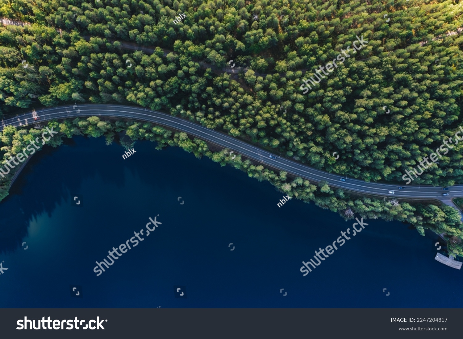 Luftbild der Straße mit grünen Wäldern durch blaues Seenwasser im Sommer Finnland. – Stockfoto