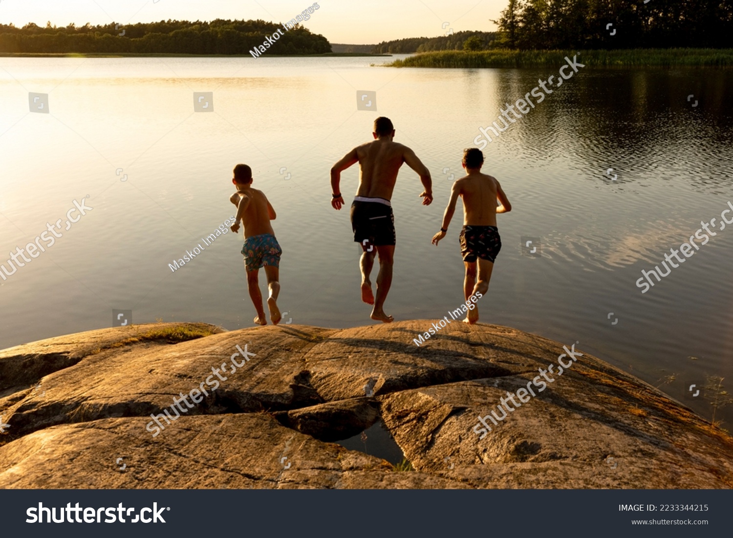 Vater und Söhne, die im Urlaub auf den See laufen – Stockfoto
