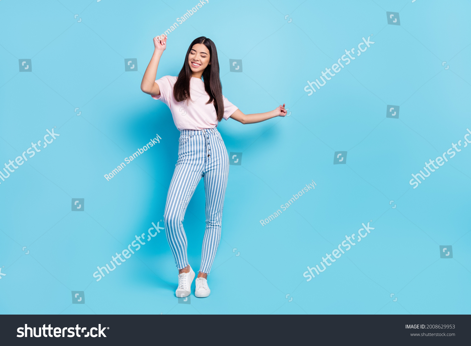 Volllange Körpergröße mit Blick auf attraktive, fröhliche, schlenderes, sorgenfreies Mädchen, das tanzt einzeln auf hellblauem Hintergrund – Stockfoto
