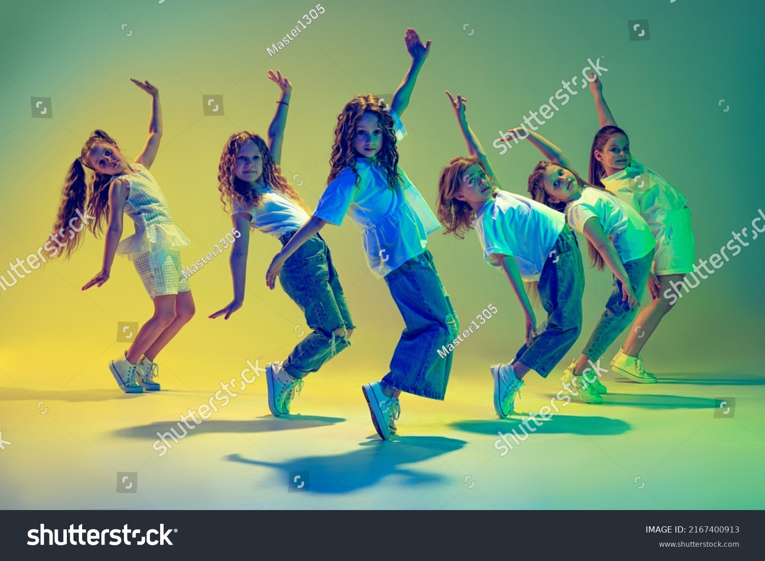 Fröhliche Kinder tanzen. Gruppe von Kindern, kleine Mädchen in sportiven, lockeren Kleidung tanzen in Choreografieklasse einzeln auf grünem Hintergrund auf gelbem Neonlicht. Konzept von Musik, Mode, Kunst – Stockfoto