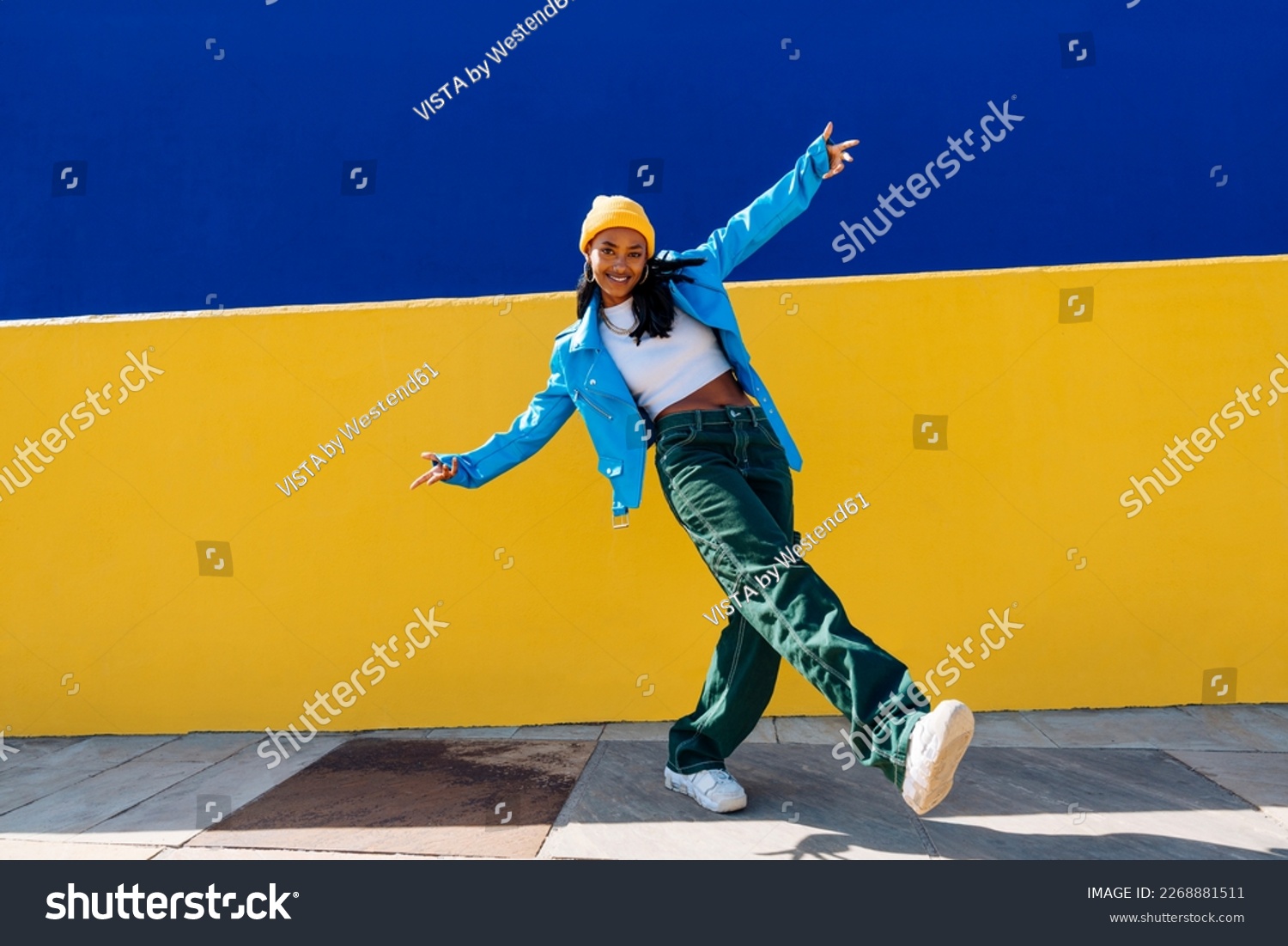 Lächelnde junge Tänzerin mit ausgestreckten Armen auf dem Fußweg – Stockfoto