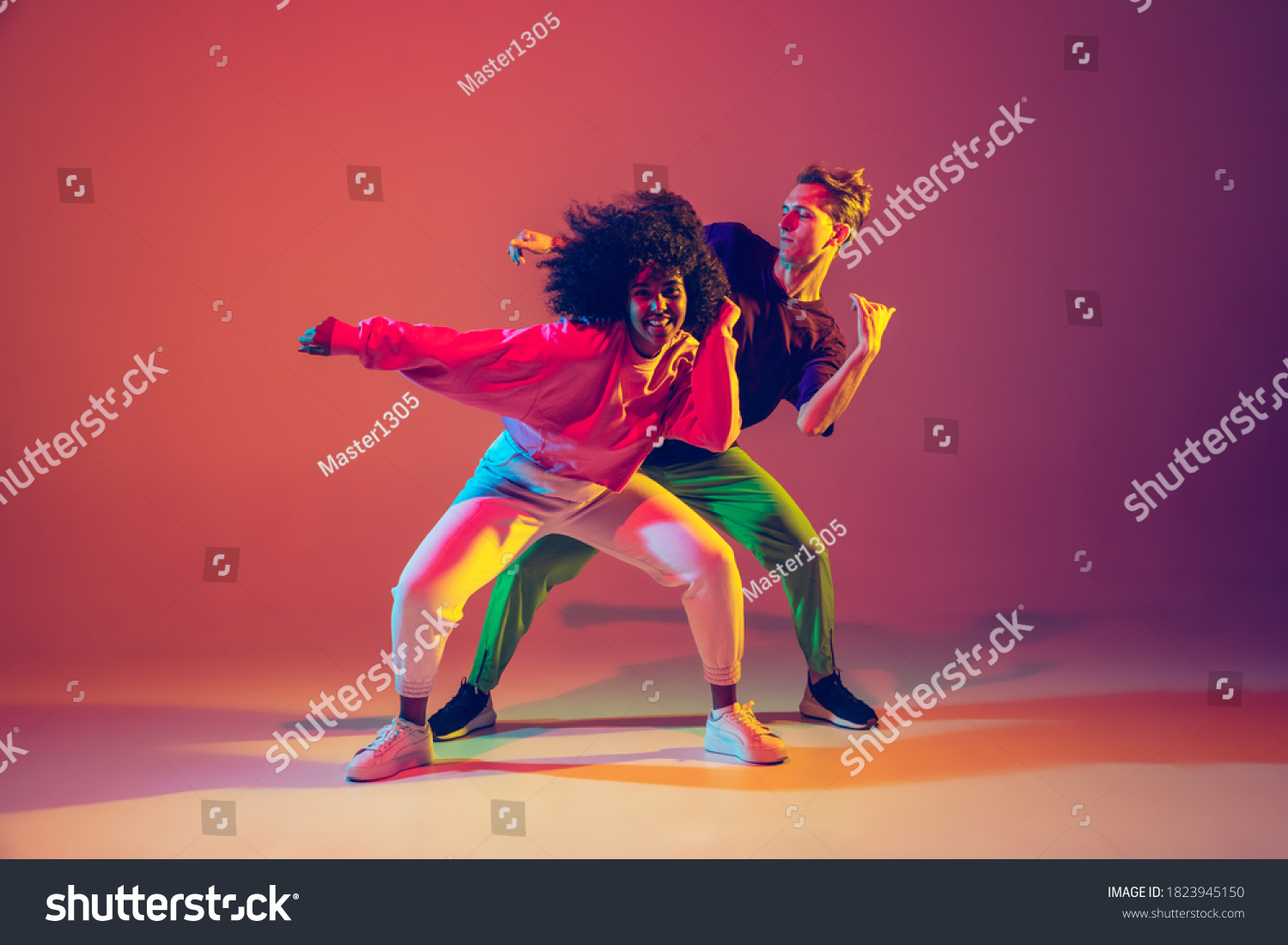 Stilvolle Mann und Frau tanzen Hip Hop in hellen Kleider auf grünem Hintergrund in der Tanzhalle im Neonlicht. Jugendkultur, Hip Hop, Bewegung, Stil und Mode, Action. Modeporträt. – Stockfoto
